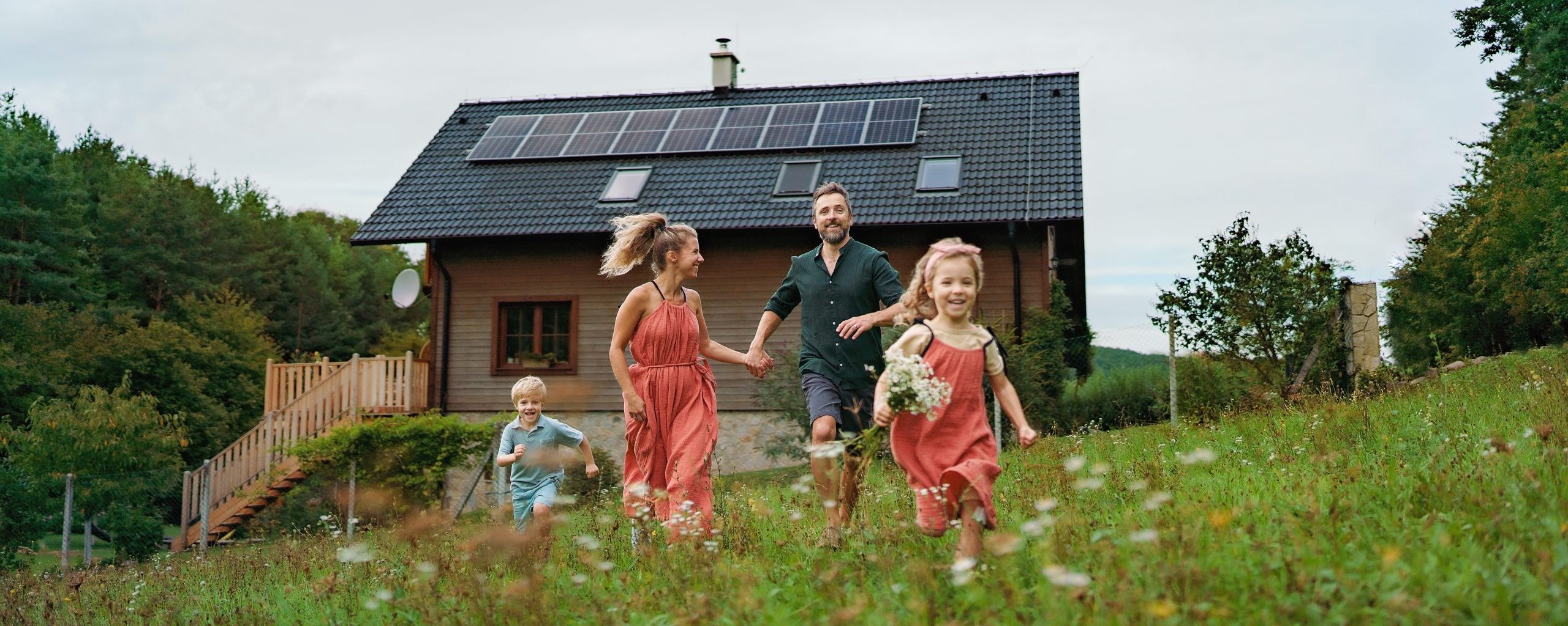 A smiling family with a solar panel system on their roof